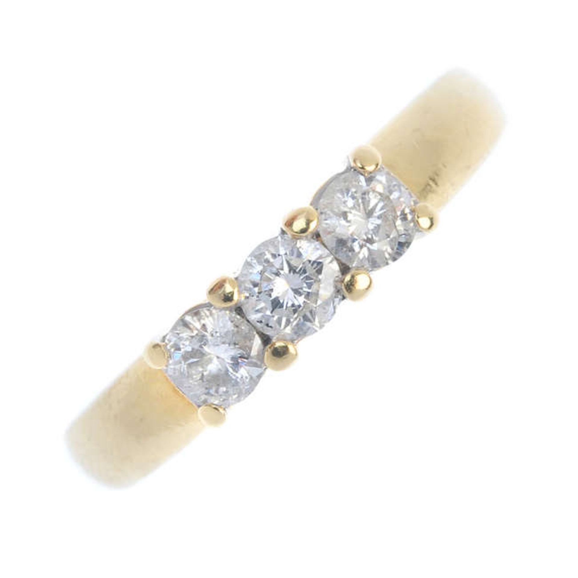 An 18ct gold diamond three-stone ring. The brilliant-cut diamonds, to the tapered band. Estimated