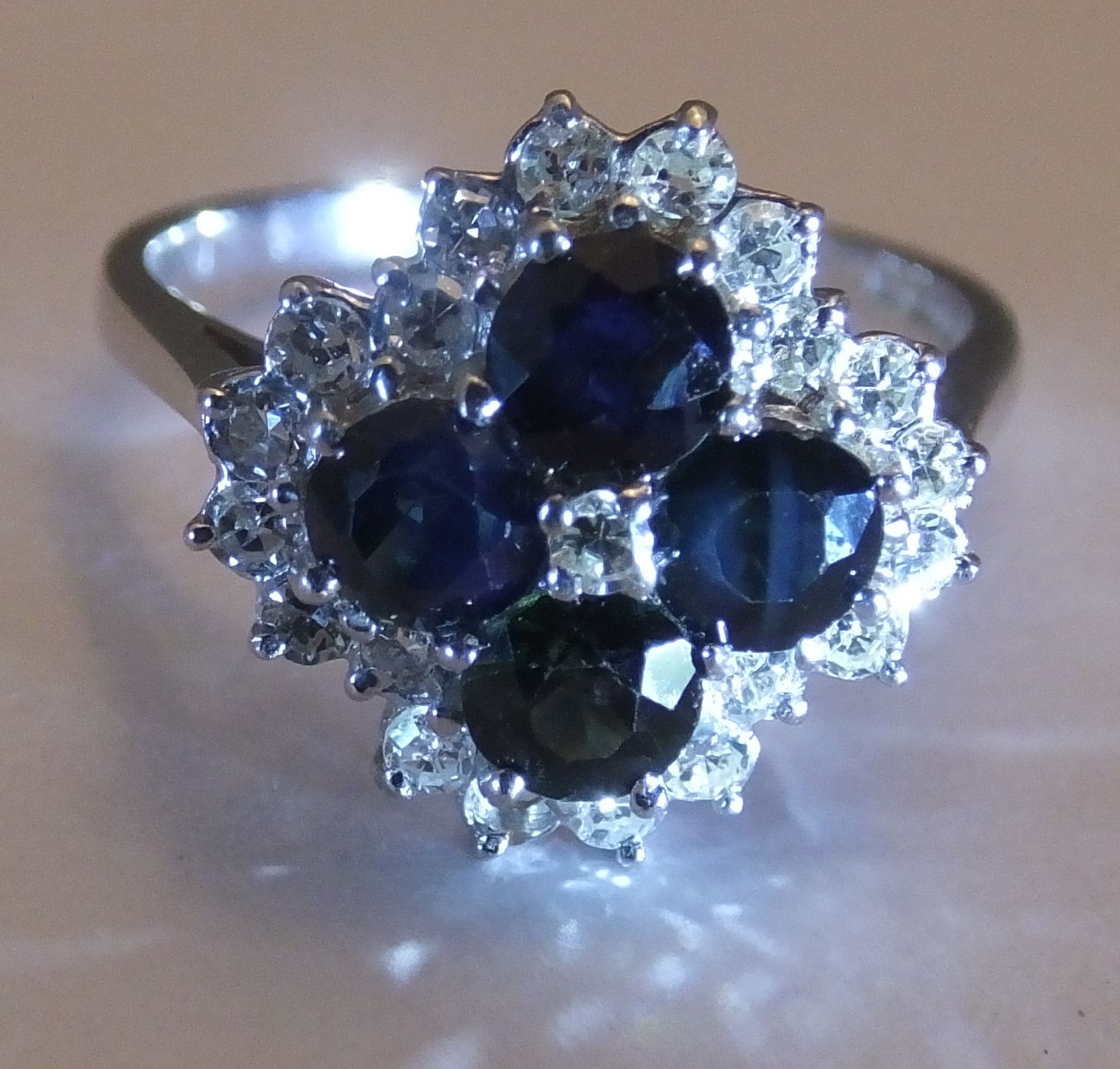 An 18ct gold sapphire and diamond cluster ring. Size O. The single-cut diamond, within a circular-