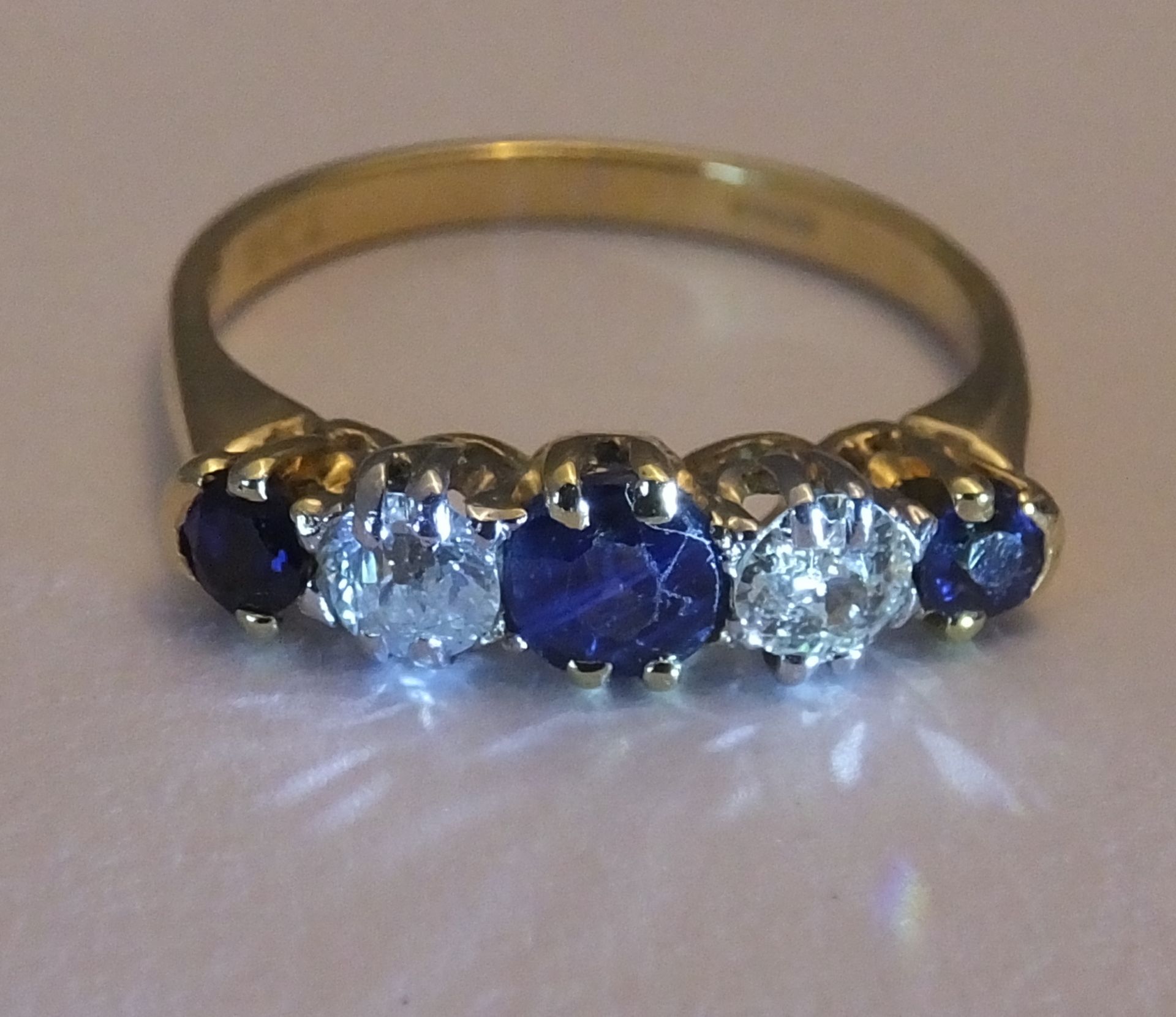 A mid 20th century 18ct gold sapphire and diamond five-stone ring. Size L. The circular-shape