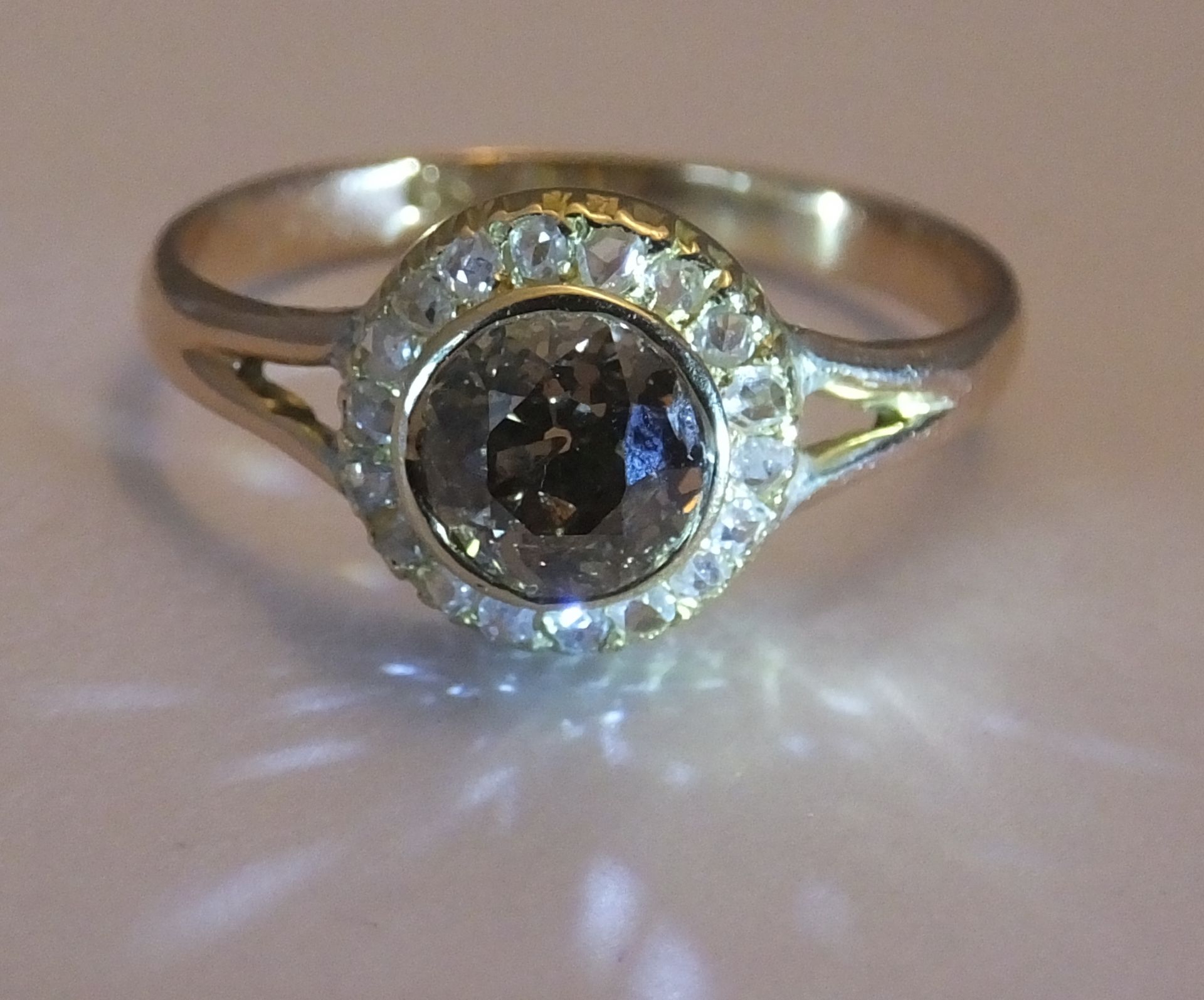 A coloured diamond and diamond cluster ring. Size R. The old-cut 'brown' diamond, within a rose-