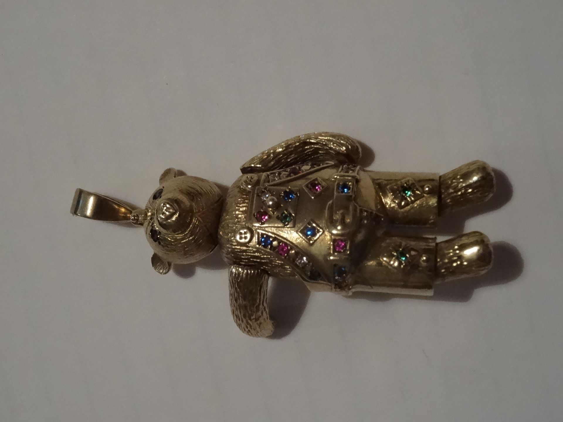 9 Carat Yellow Gold Moveable Teddy Bear Pendant. Set with 26 Stones in green, clear, red and blue.
