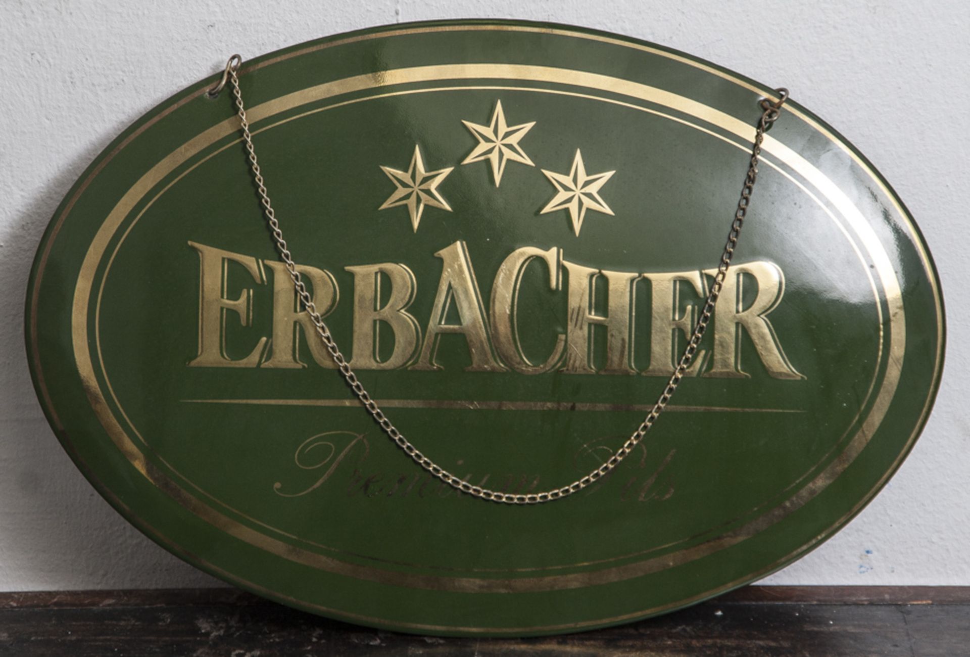 Emailschild, "Erbacher - Premium Pils", goldene Schrift auf grünem Grund, oval. Ca. 30 x45 cm.
