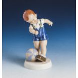 Figur, Junge mit Ball, Feinsteinzeug. Polychrom gefasst. H. ca. 15,5 cm.