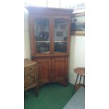 An oak corner cabinet in two pieces, glazed.