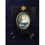 A framed miniature portrait of a young girl with a brass stand. Signed on the reverse by M. Thomas.