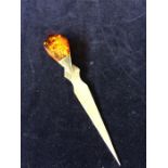 A silver letter opener with amber style top.