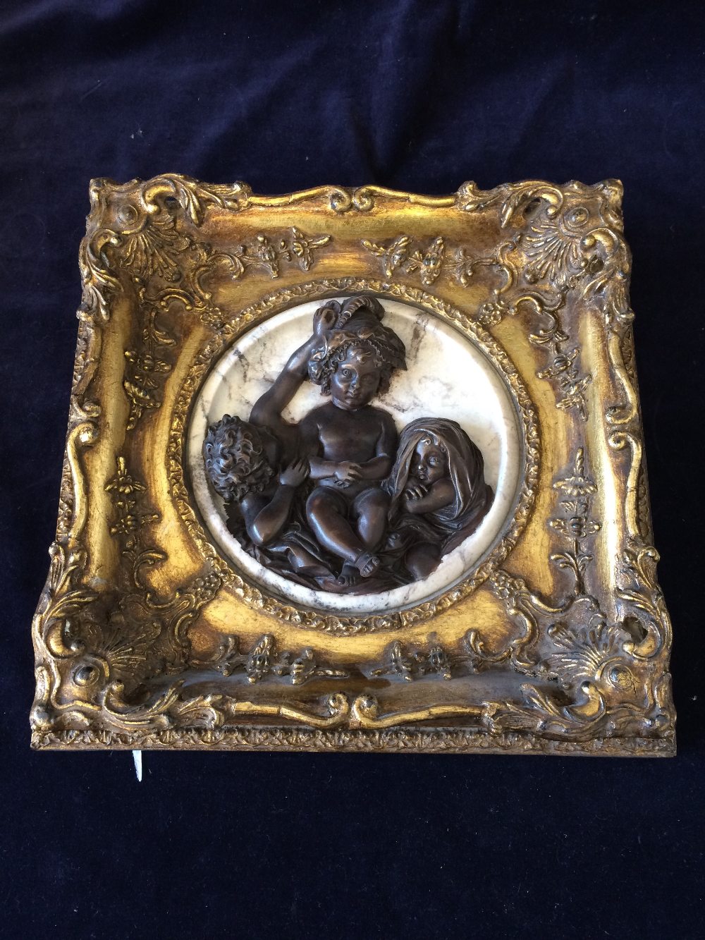 A Bronze and stone plaque featuring cherubs