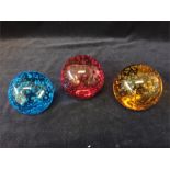 Three blown glass paperweights in orange, red and blue