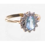 A 9ct gold blue topaz and diamond set cluster ring
The central oval mixed cut blue topaz within a