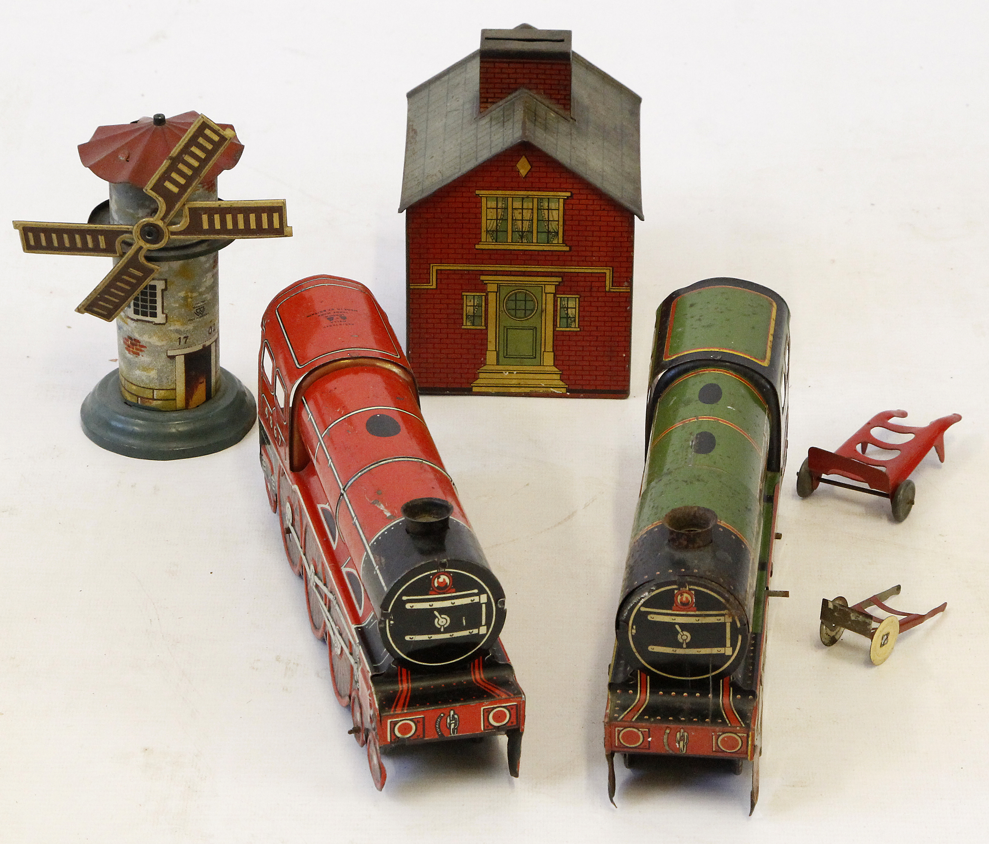 Four tinplate items 
Comprising a money box in the form of a house with detailed tin printing,