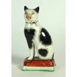 A mid to late 19th Century Staffordshire cushion figure
Depicting a black and white cat seated on