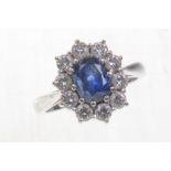 A 18ct white gold sapphire and diamond set cluster ring 
The central oval mixed cut sapphire of