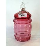 A cranberry glass lidded biscuit barrel of ovoid form.