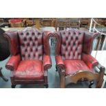 A Pair of ox blood red leather button back and wing back fireside armchairs.