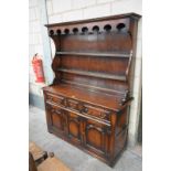 A Reproduction George III style oak dresser the high back with a cavetto cornice above a shaped