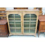 A 20th Century bur walnut 2 door display cabinet raised on ogee bracket feet.