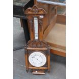 A Victorian carved oak wall barometer and thermometer with a white enamelled dial the case