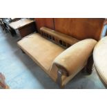 An Early 20th century oak and brown velour chaise lounge with a padded rail raised on stylised