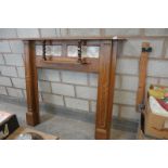 An Early 20th century oak fire surround with a tiled back above a secondary shelf with outset