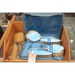 A Cased enamelled dressing table set and a four piece silver backed dressing table set.