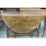 A 1930's Oval oak drop leaf dining table on barley twist supports.