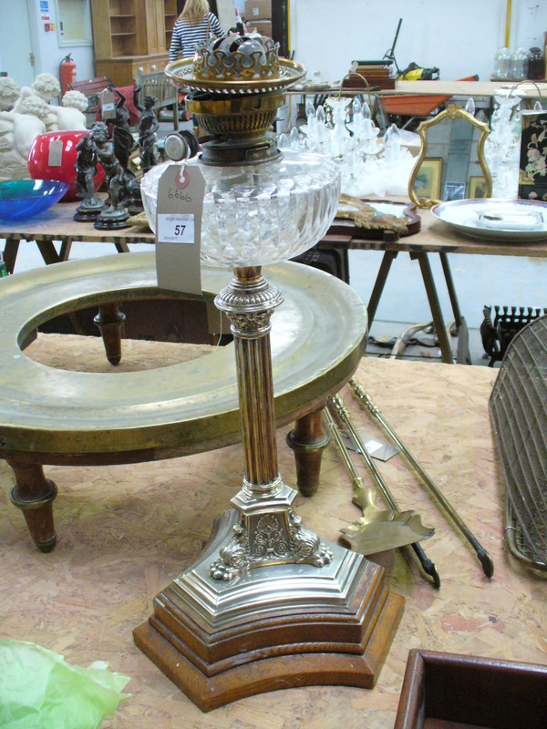 A Victorian silver plated oil lamp with a clear glass reservoir raised on a Corinthian column,