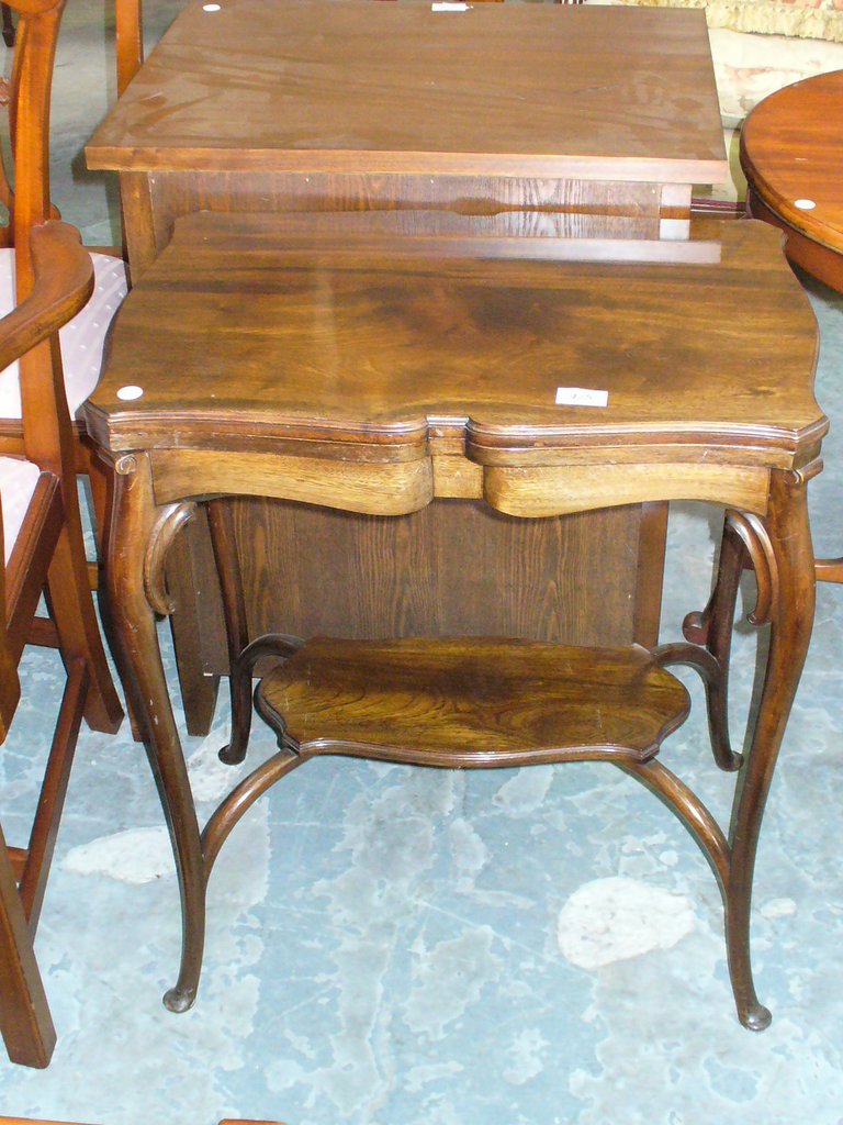 An early 20th century shaped walnut folding games table of small proportions raised on curvillinear