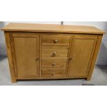 A pale oak sideboard with four drawers to the centre flanked either side by cupboard doors,