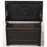 A 20th century stained oak monks bench with carved floral decoration, length 92cm.