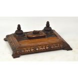 A Victorian carved oak rectangular inkstand with two inkwells and lidded container decorated with