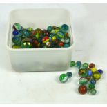 A collection of predominantly green glass marbles with coloured decoration to the inside,