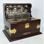 An Edwardian oak tantalus/compendium with plated mounts, the raised back section set with three