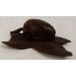 A Black Forest carved oak inkwell and pen rest modelled as a pine cone on leaves, with hinged lid