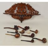 An early 20th century fret cut wall mounted pipe rack decorated with oak leaves and acorns,