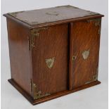 A 1920s oak smoker's cabinet with electroplated mounted corners and two shields on the pair of