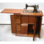 A 1920s/30s cabinet Singer treadle sewing machine with folding extension leaf,