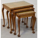 A nest of three 20th century walnut glass topped tables with knee carved cabriole legs to ball and