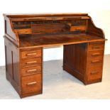 An early 20th century oak roll top desk the serpentine tambour revealing fitted interior with