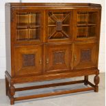 An early 20th century oak court style cupboard with three glazed doors to the top,