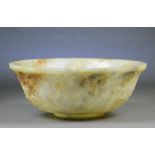 A large Chinese pale celadon and russet included jade bowl decorated to the exterior with chilong