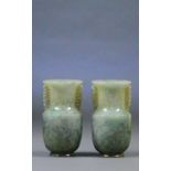 A pair of Chinese jade baluster vases with pierced scrolling handles and plain mottled green bodies,