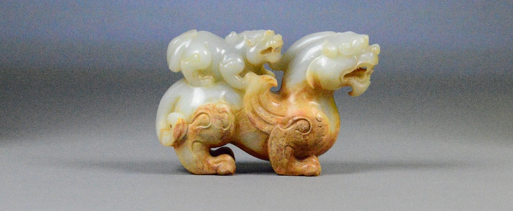 A Chinese pale celadon and russet included carved jade model of a dragon with small dragon upon the