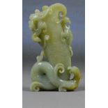 A Chinese pale celadon and slight russet included carved jade vase moulded as a dragon with further