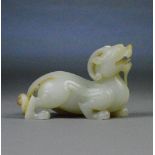 A Chinese mutton fat jade and russet included carved figure of a stylised dragon, length 16.5cm.