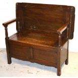 An early 20th century oak monks bench of simple form with lift up seat on block supports,