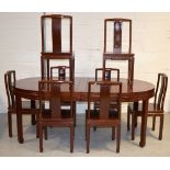 A 20th century Oriental hardwood dining table with two central leaves and frieze carved in the