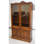 A 20th century oak bookcase with shaped pediment twin glazed doors opening to reveal interior