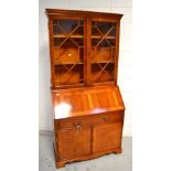 A reproduction yew wood bureau bookcase two astragal glazed doors above fitted interior,