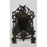 A 20th century cast iron framed mirror decorated with cherubs and scrolling branches and pillars,