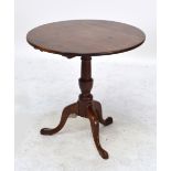 A mahogany circular tilt top occasional table with turned support and tripod outswept legs,